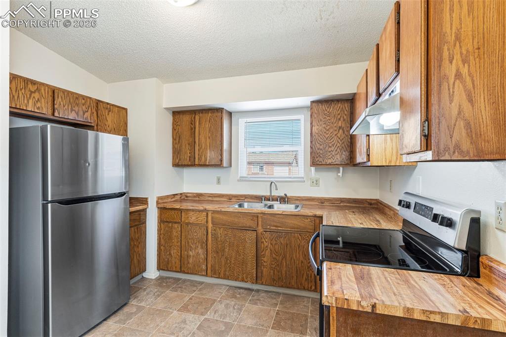 6745 Parkridge Court Colorado Springs, CO 80915 - Photo 8 of 23 a kitchen with a sink a refrigerator and cabinets