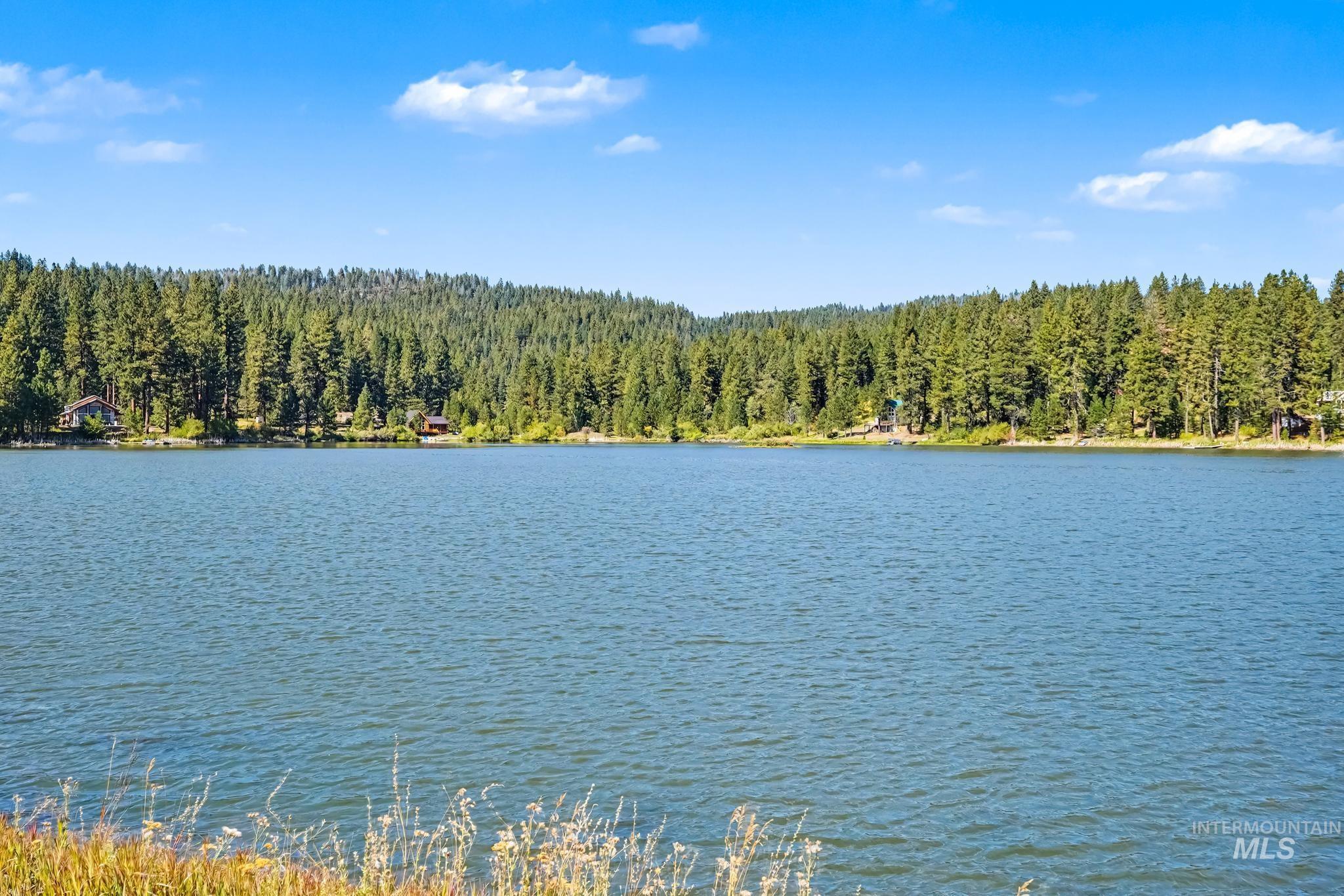 106 Wilderness Lake Road Cascade, ID 83611 - Photo 32 of 35 Expansive lake with surrounding evergreen forests and clear blue sky