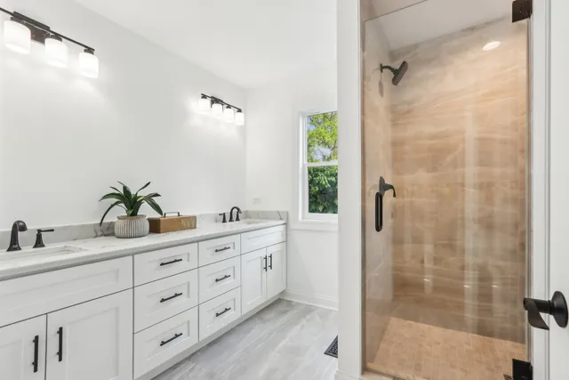 a bathroom with a granite countertop sink a mirror a glass door a shower and vanity