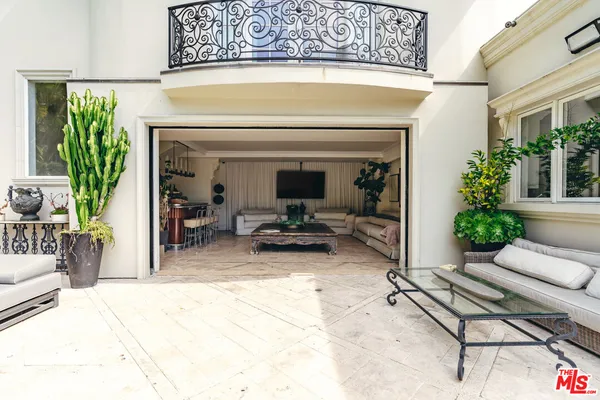 a living room with stainless steel appliances furniture a flat screen tv and a large window