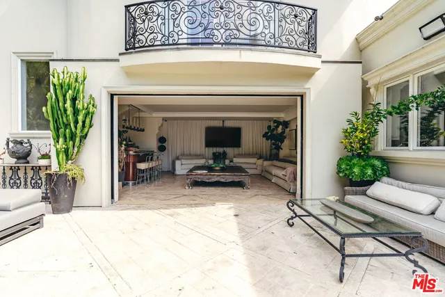 a living room with stainless steel appliances furniture a flat screen tv and a large window