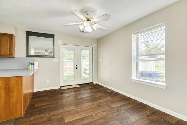 a view of an empty room with wooden floor and a window