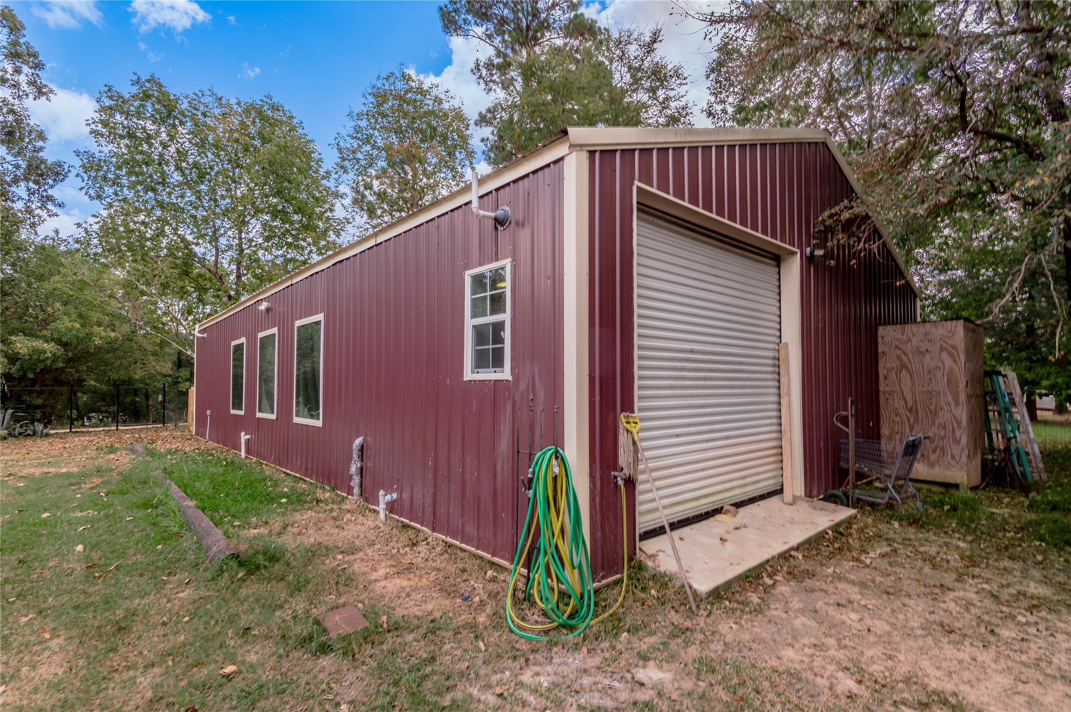 47-57 Stage Coach Road Coldspring, TX 77331 - Photo 42 of 50 Spacious building with a roll-up garage door, perfect for storage, Air B&B, or a workshop, set in a serene wooded area.