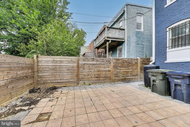a backyard of a house with large trees and brick walls