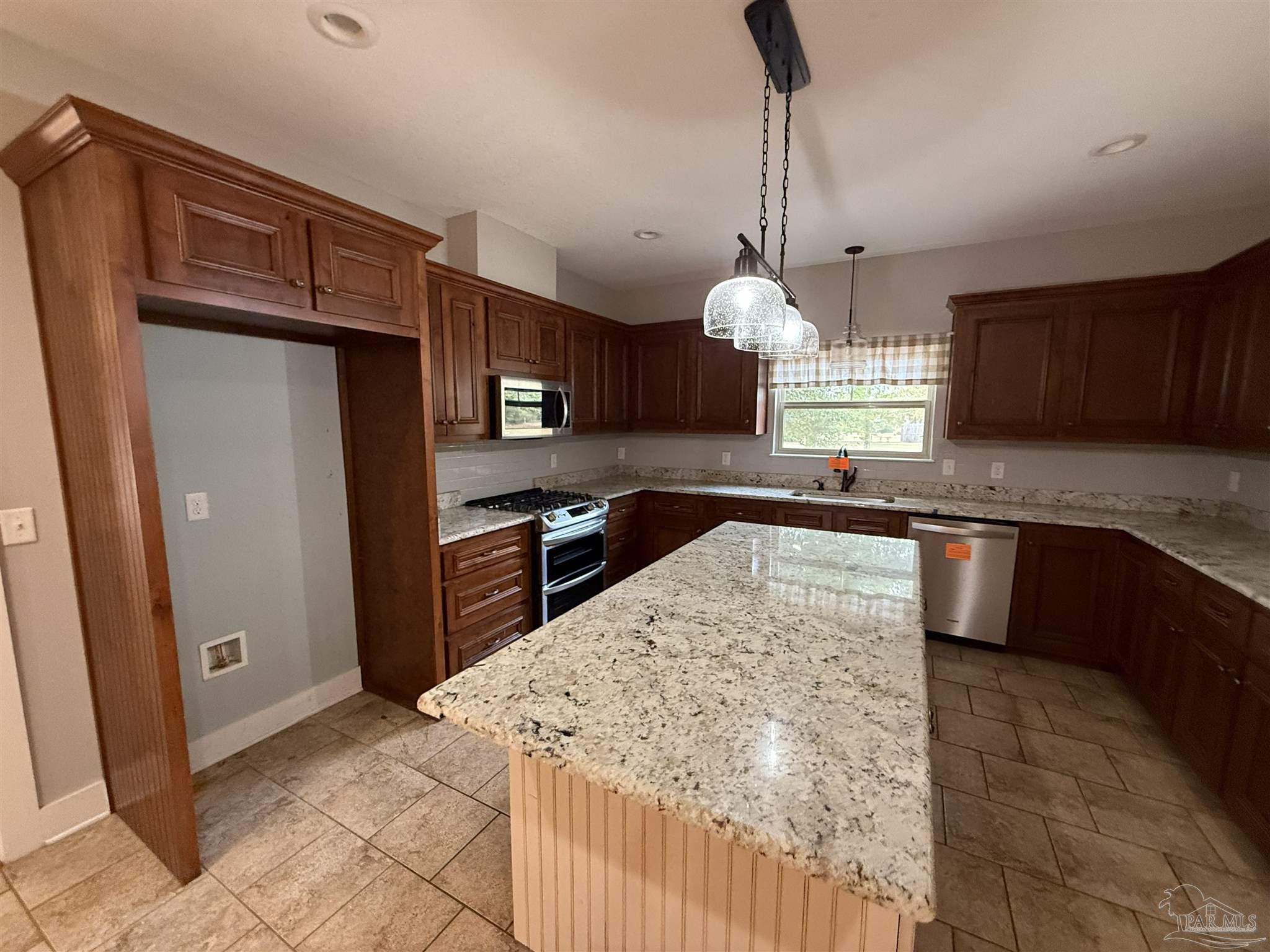 7223 Martin Road Milton, FL 32570 - Photo 18 of 28 a kitchen with stainless steel appliances granite countertop a sink a stove a refrigerator cabinets a dining table and chairs