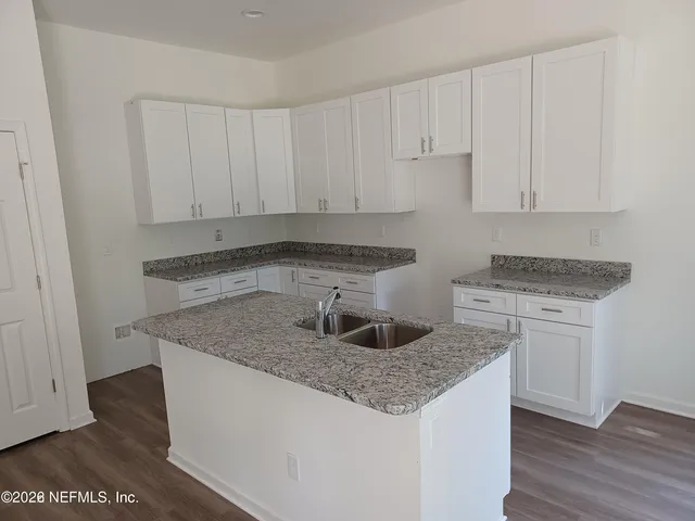 a kitchen with granite countertop a sink and white cabinets