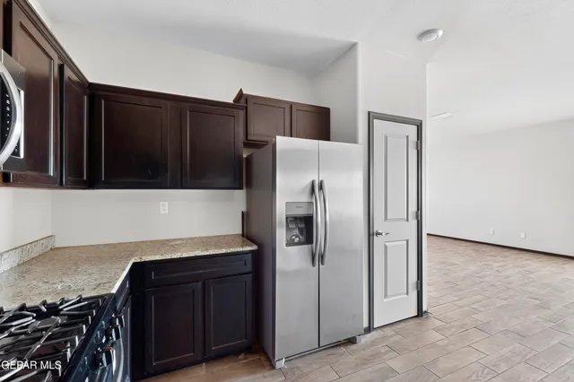 a view of a refrigerator in kitchen and an empty room