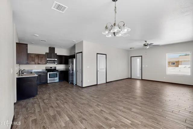 a view of a kitchen with a stove wooden cabinet a chandelier and wooden floor