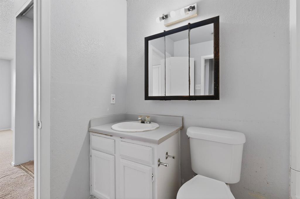 9467 Olde Towne Row Dallas, TX 75227 - Photo 23 of 26 a bathroom with a toilet sink and mirror