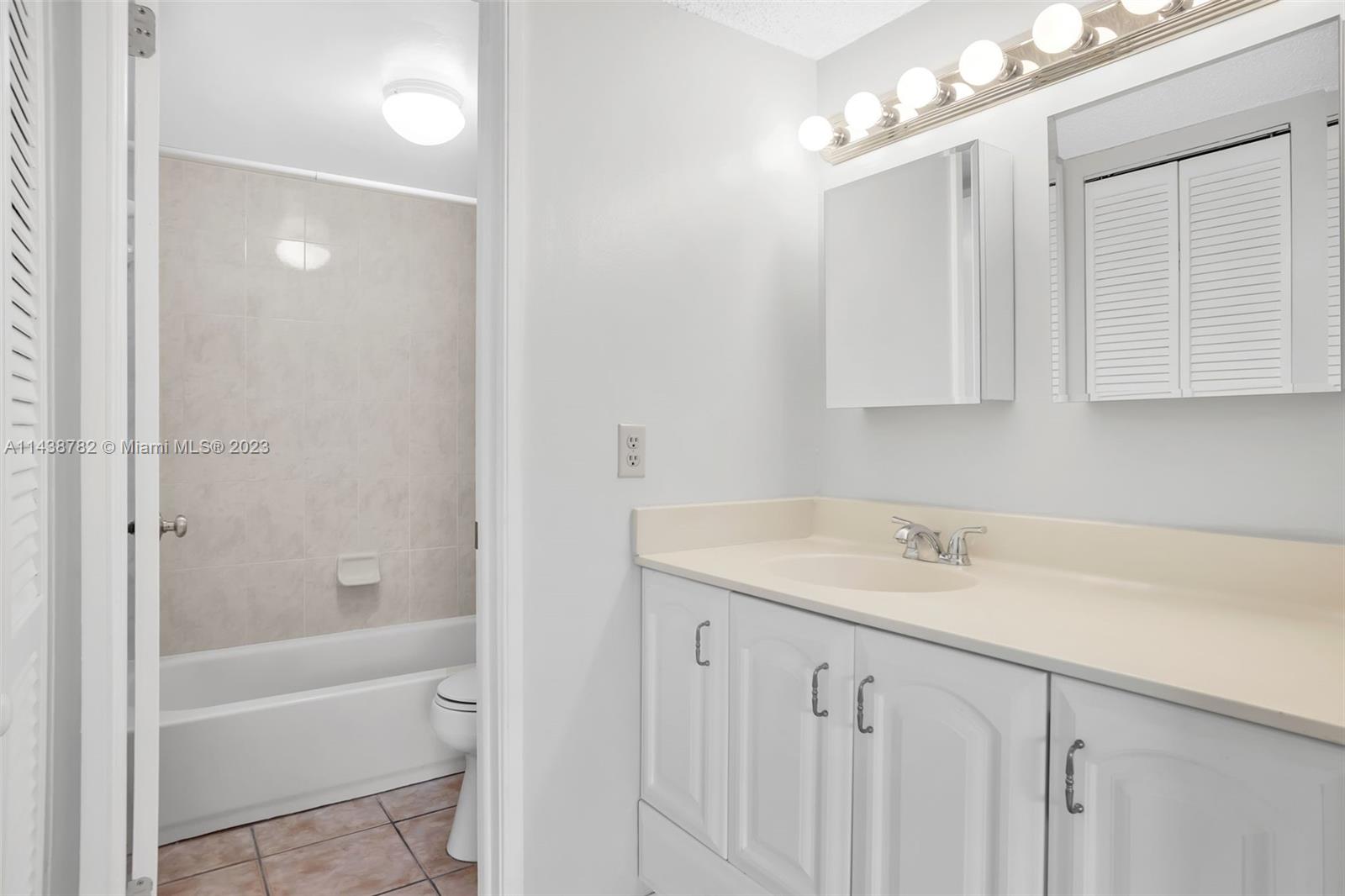 9140 Southwest 123rd Court, Unit 210Q Miami, FL 33186 - Photo 16 of 26 a bathroom with a sink double vanity mirror and a bathtub