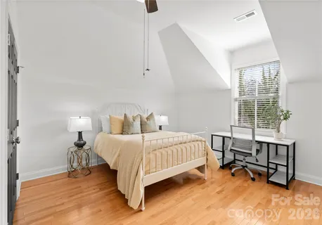a spacious bedroom with a bed and wooden floor