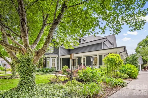 a view of a white house with large windows and a small yard