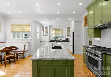 a kitchen with stainless steel appliances granite countertop table chairs sink and cabinets