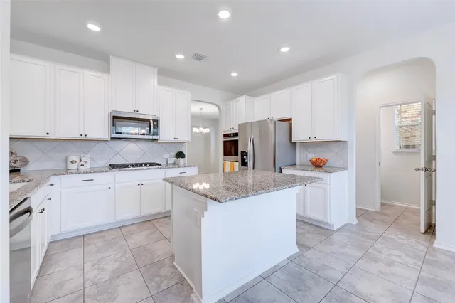 a open kitchen with stainless steel appliances granite countertop a refrigerator and a stove top oven