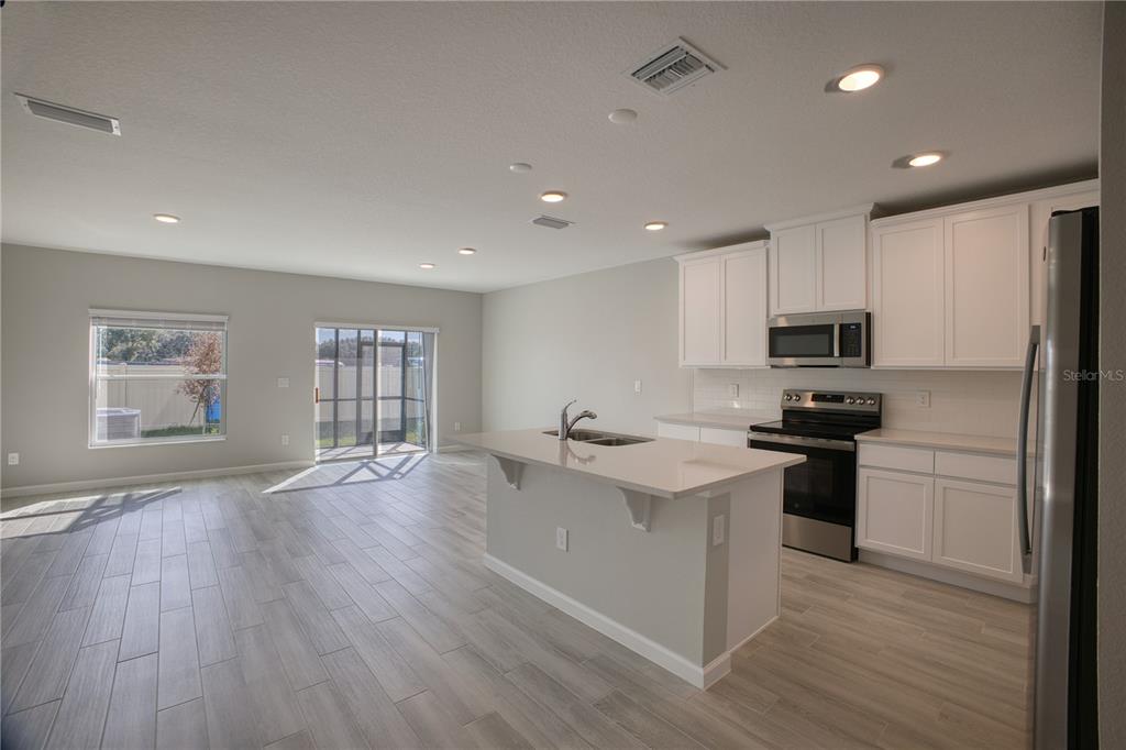4188 Campsite Loop Orlando, FL 32824 - Photo 5 of 38 a kitchen with stainless steel appliances granite countertop a refrigerator a sink dishwasher a stove and white countertops with wooden floor