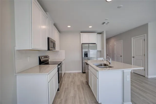 a kitchen that has a sink a stove and cabinets