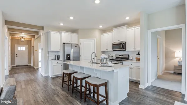 a kitchen with stainless steel appliances granite countertop a refrigerator a stove top oven a sink dishwasher and white cabinets with wooden floor