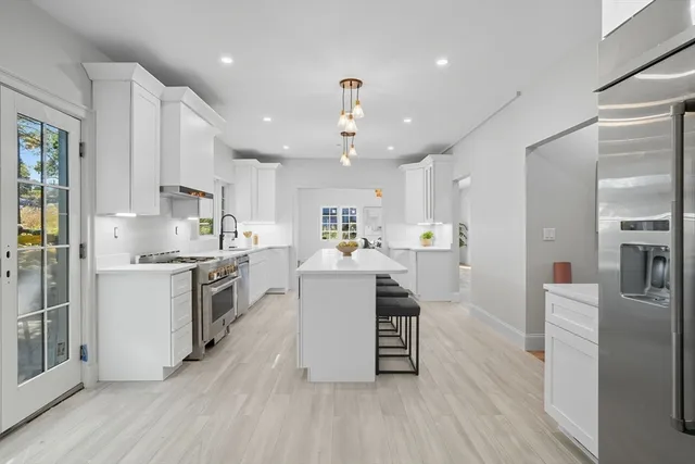 a large white kitchen with lots of counter space a sink stainless steel appliances and cabinets