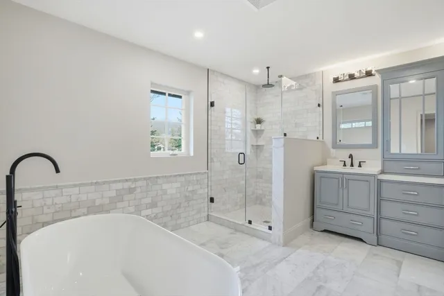 a spacious bathroom with a double vanity sink mirror and bathtub