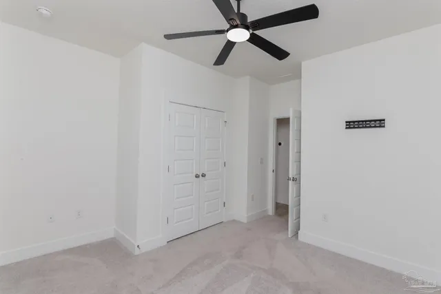an empty room with closet and a ceiling fan