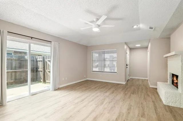 an empty room with wooden floor a fireplace and a window