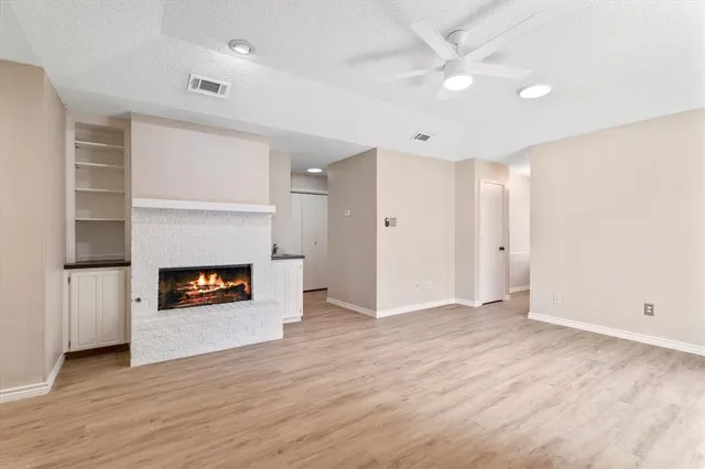 a view of an empty room with wooden floor fireplace and a window