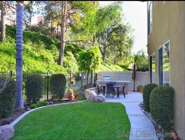 a view of a patio with table and chairs potted plants and large tree