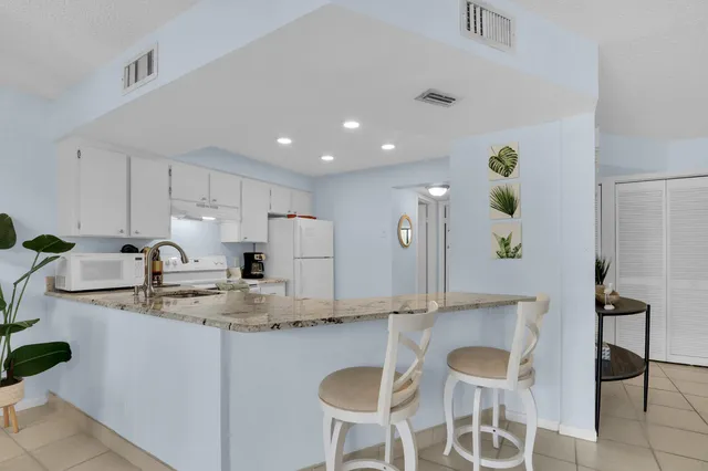 a kitchen with kitchen island granite countertop a sink and white cabinets