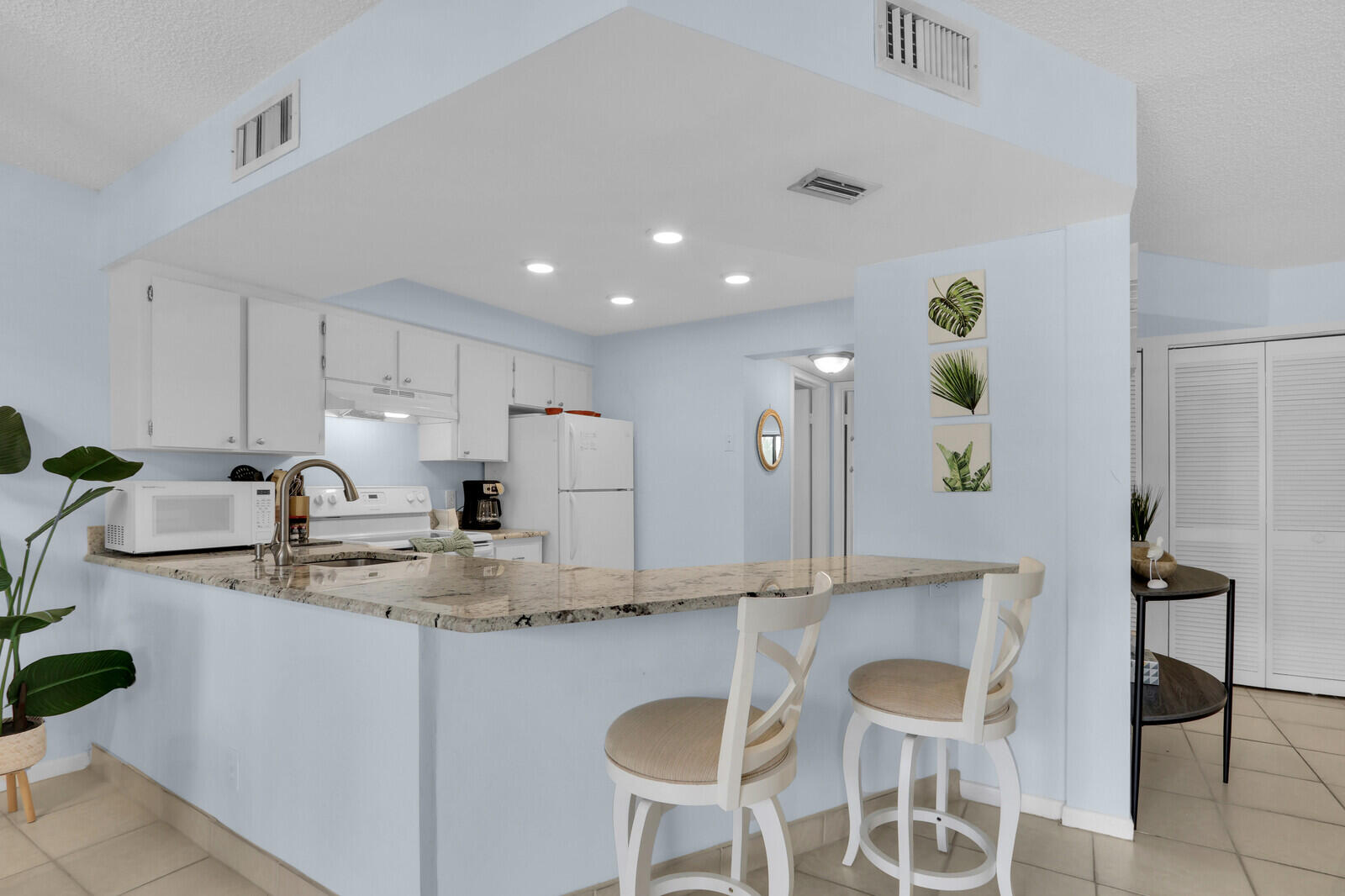 1605 Highway 1, Unit A204 Jupiter, FL 33477 - Photo 10 of 32 a kitchen with kitchen island granite countertop a sink and white cabinets