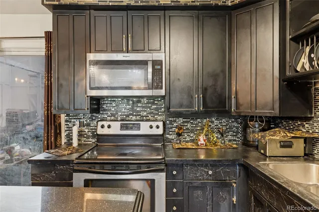 a kitchen with granite countertop a stove a sink and a microwave