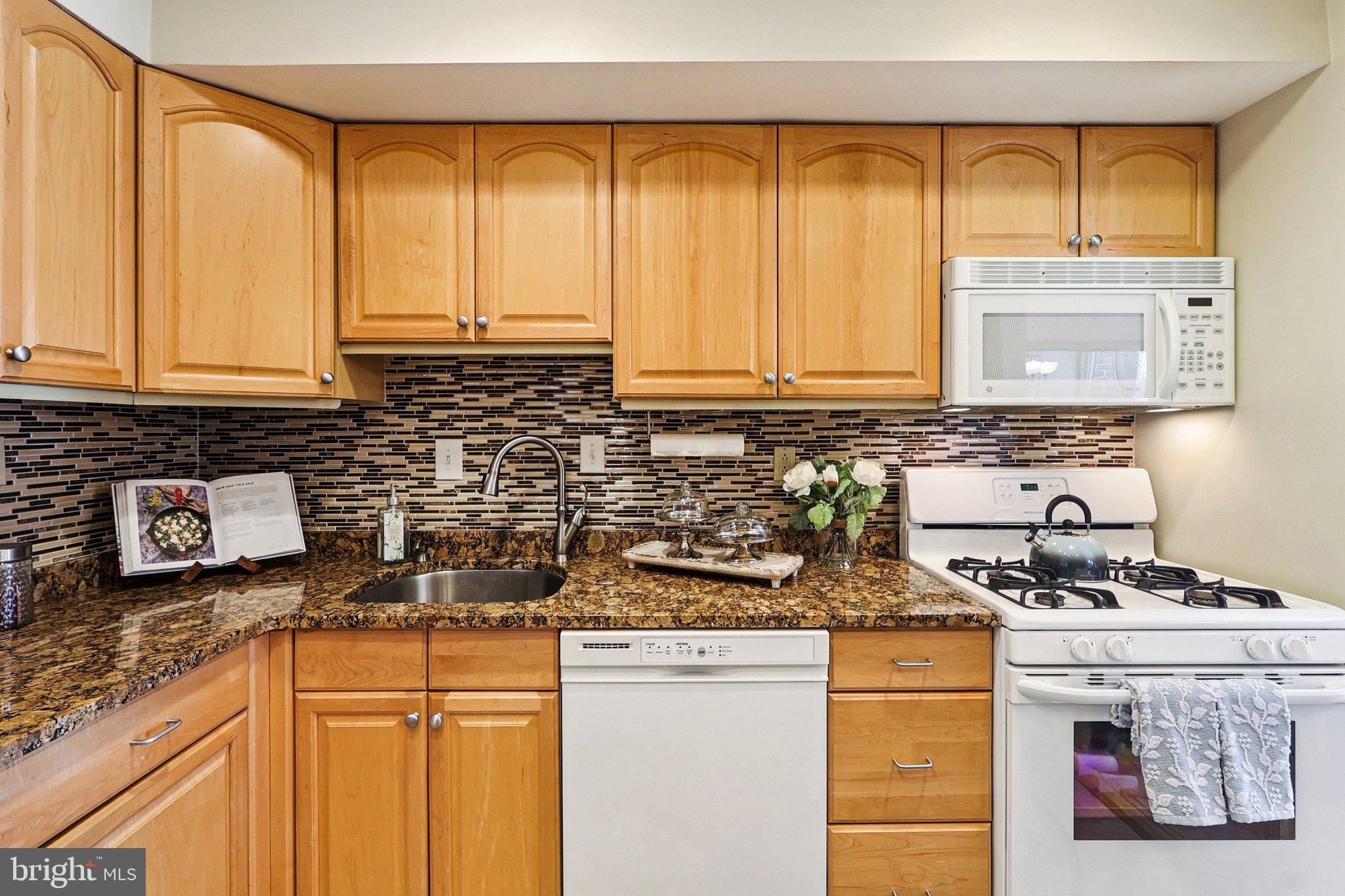 9900 Georgia Avenue, Unit 27217 Silver Spring, MD 20902 - Photo 16 of 50 a kitchen with stainless steel appliances granite countertop a sink a stove and a microwave