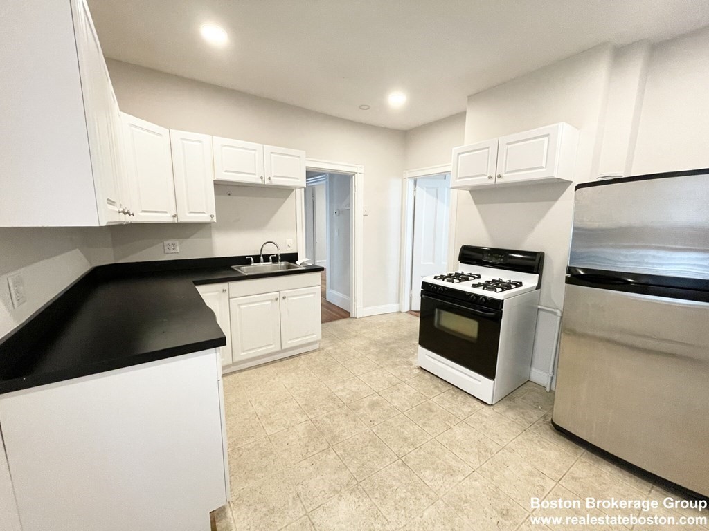 a kitchen with granite countertop a sink a stove and refrigerator