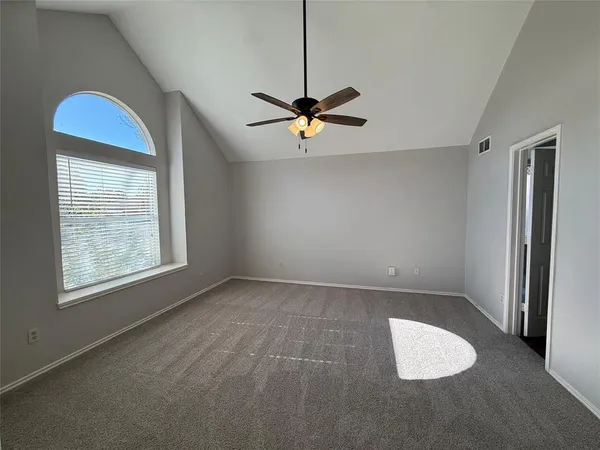 an empty room with windows and fan