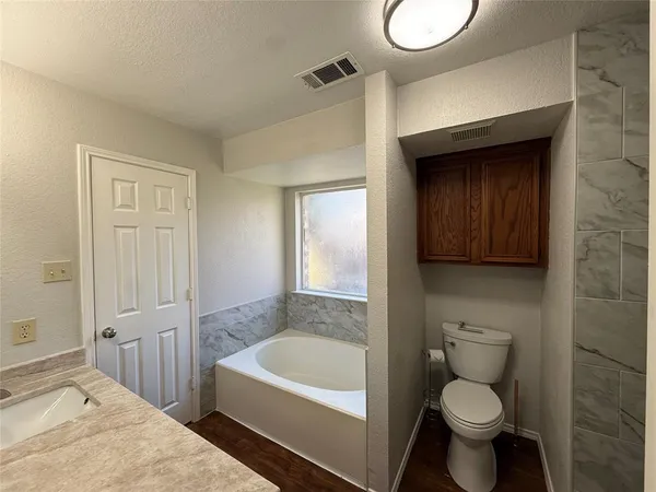 a bathroom with a granite countertop toilet and a bathtub