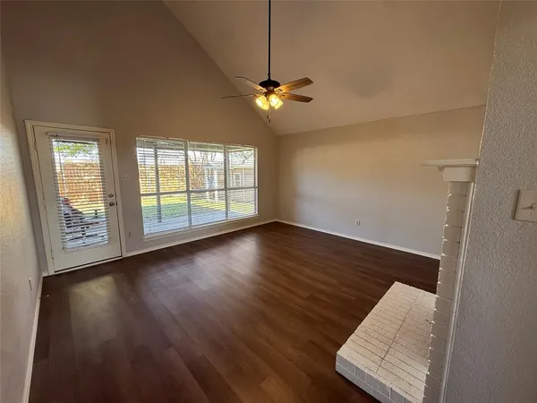 a view of an empty room with window and wooden floor