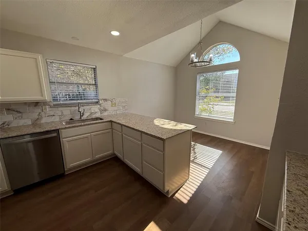 a kitchen with granite countertop a stove a sink and dishwasher with wooden floor