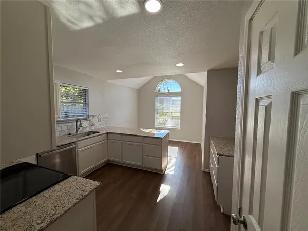 a kitchen with stainless steel appliances granite countertop a refrigerator a sink dishwasher a stove and white countertops with wooden floor