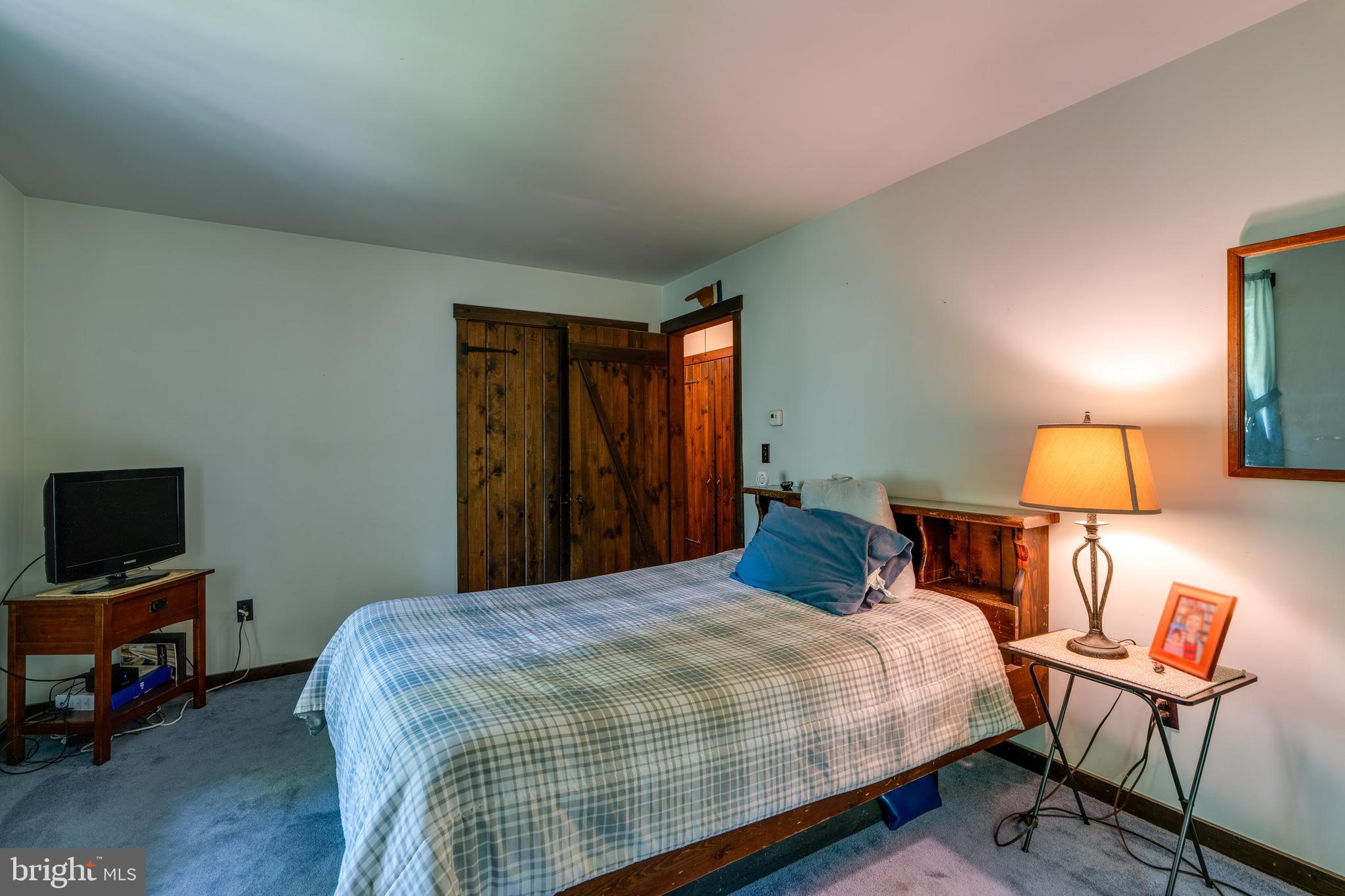 135 Fraelich Road Denver, PA 17517 - Photo 36 of 53 a bedroom with a bed a lamp and a flat screen tv