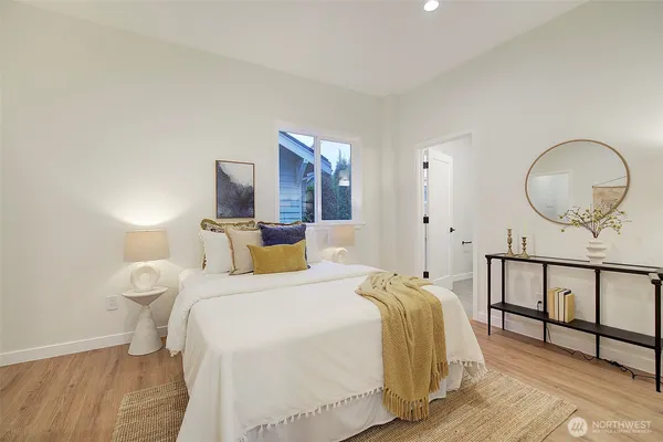 a bedroom with a bed a mirror and a potted plant