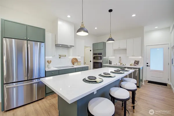 a kitchen with stainless steel appliances granite countertop a sink a stove a refrigerator and chairs