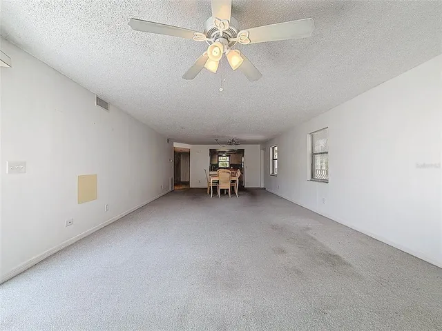 an empty room with windows and chandelier fan