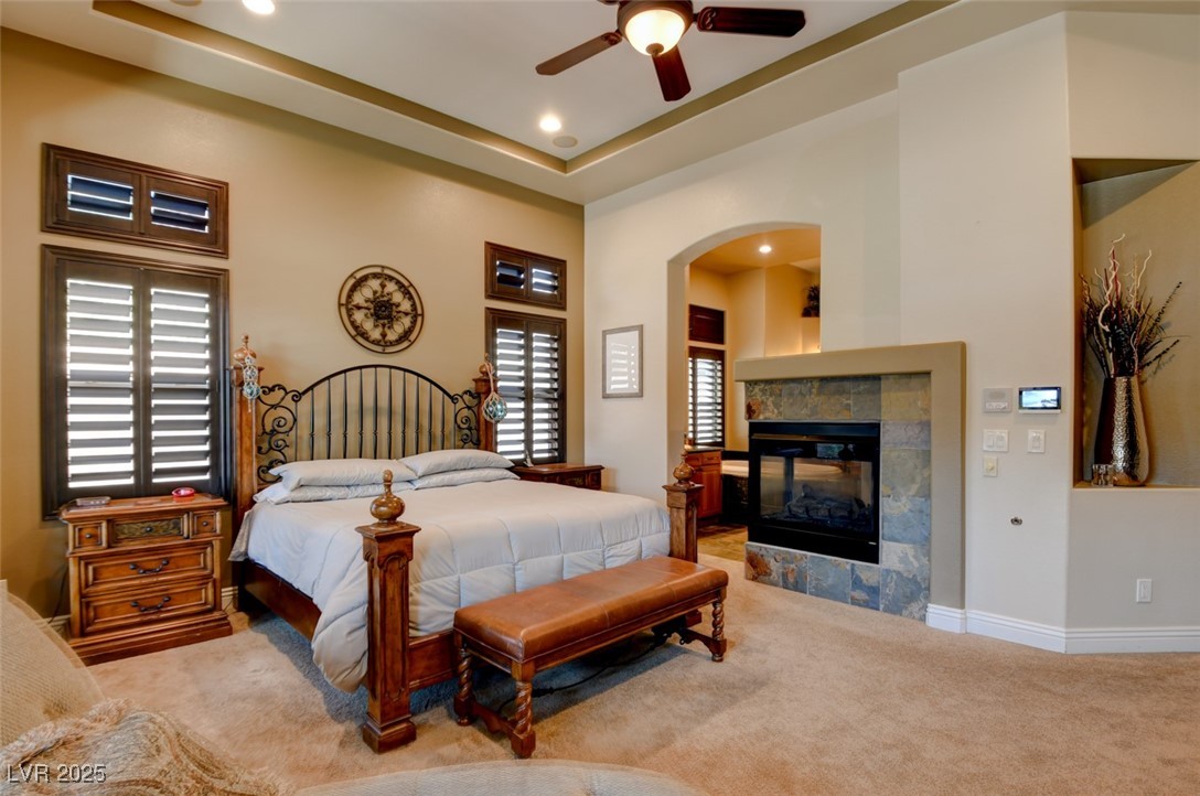 8465 West Picket Ridge Court Las Vegas, NV 89143 - Photo 21 of 51 Primary bedroom with direct access to the ensuite bathroom featuring a cozy three-way fireplace