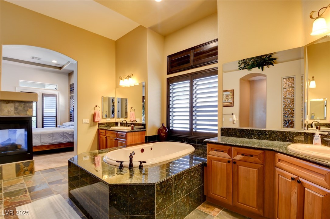8465 West Picket Ridge Court Las Vegas, NV 89143 - Photo 23 of 51 Primary bathroom featuring dual vanities and an oversized jetted, heated hot tub for ultimate relaxation