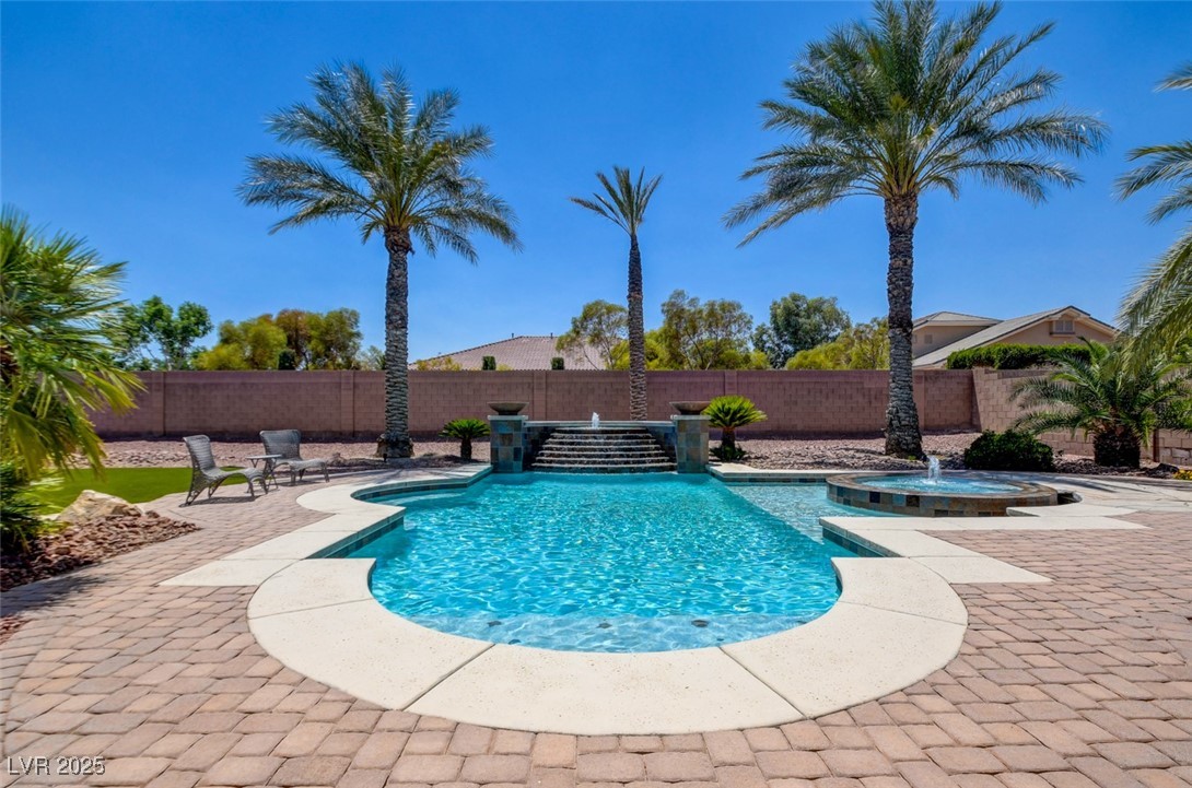 8465 West Picket Ridge Court Las Vegas, NV 89143 - Photo 42 of 51 Resort-style pool with spa and stunning water feature, surrounded by lush desert palms