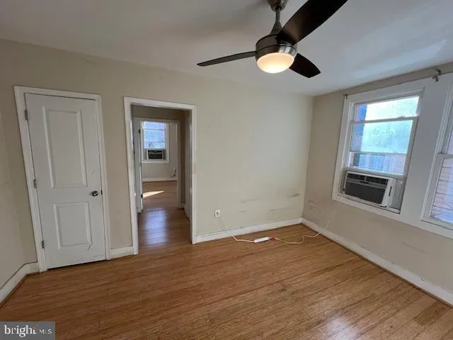 an empty room with wooden floor cabinet and windows