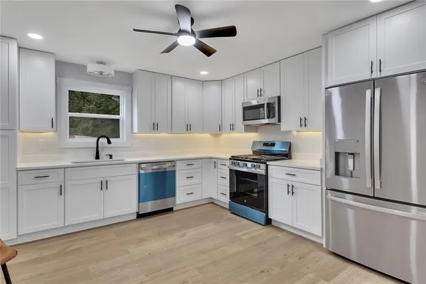 a kitchen with granite countertop a refrigerator stove top oven and sink