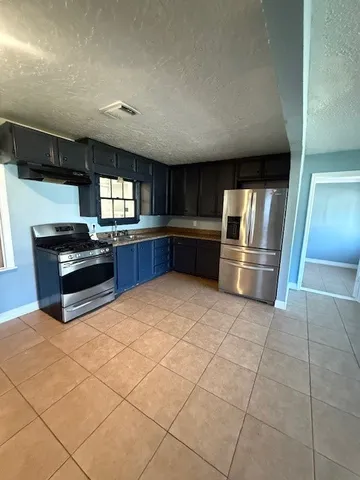 a kitchen with granite countertop a refrigerator and a stove top oven