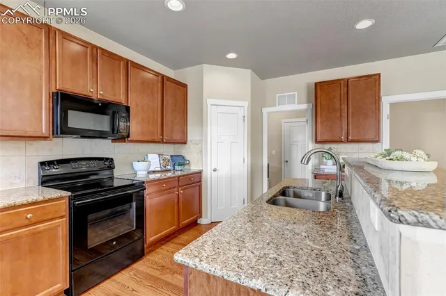 a kitchen with granite countertop a stove top oven microwave and cabinets