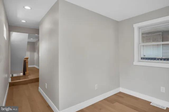 a view of a hallway with wooden floor and a bathroom