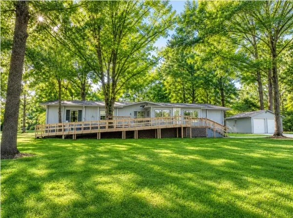 a view of a wooden house with a big yard and large trees